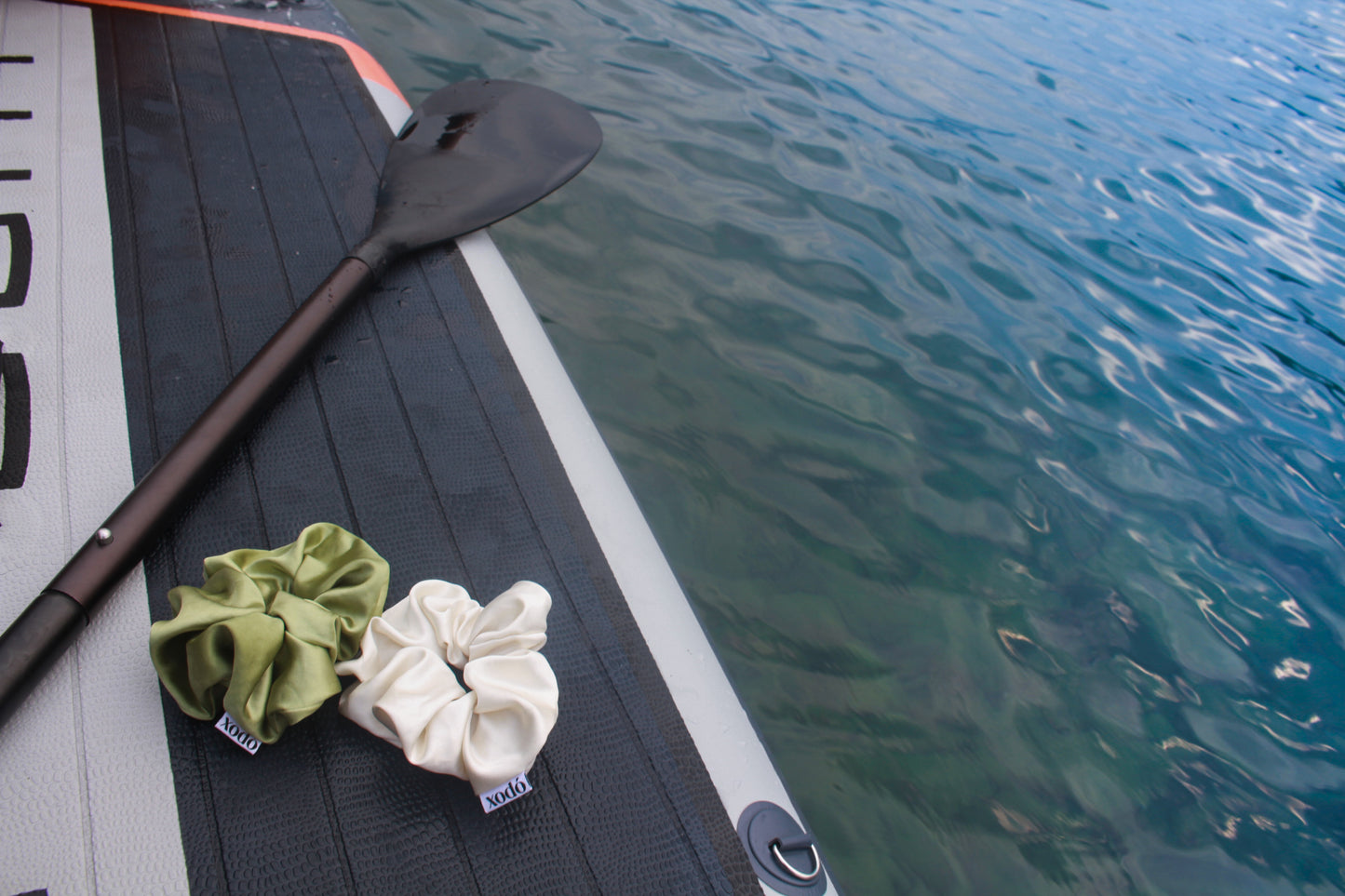 Two scrunchies on a paddle with water in the background