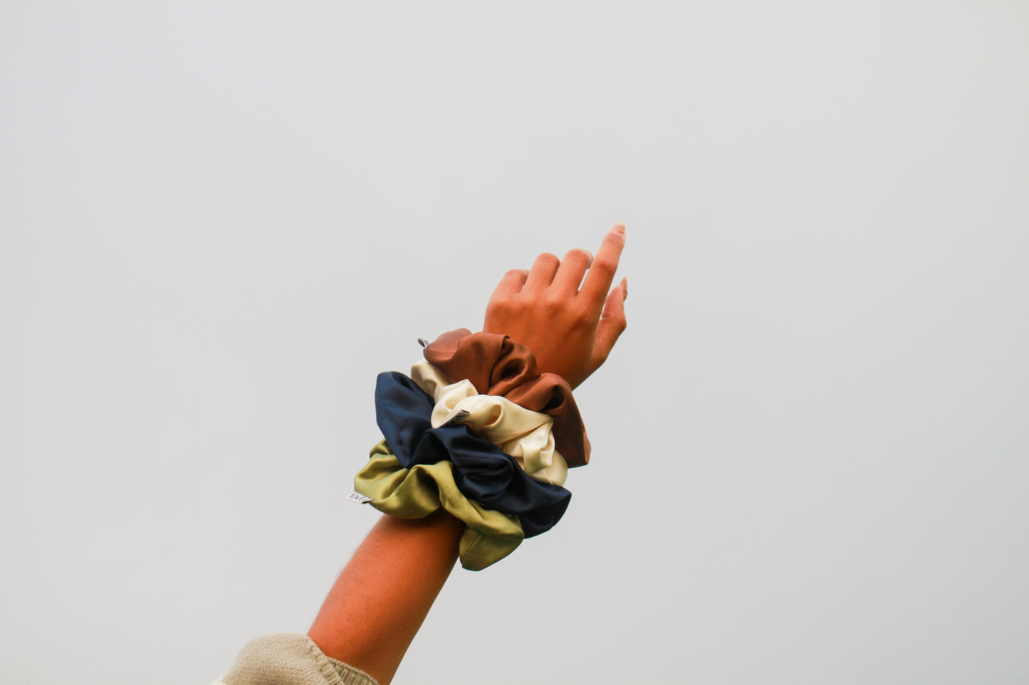 Hand wearing a wrist corsage with multiple scrunchies on a plain background