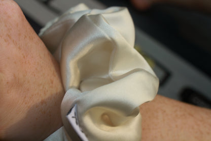 Close-up of a wrist wearing a white scrunchy with a blurred background
