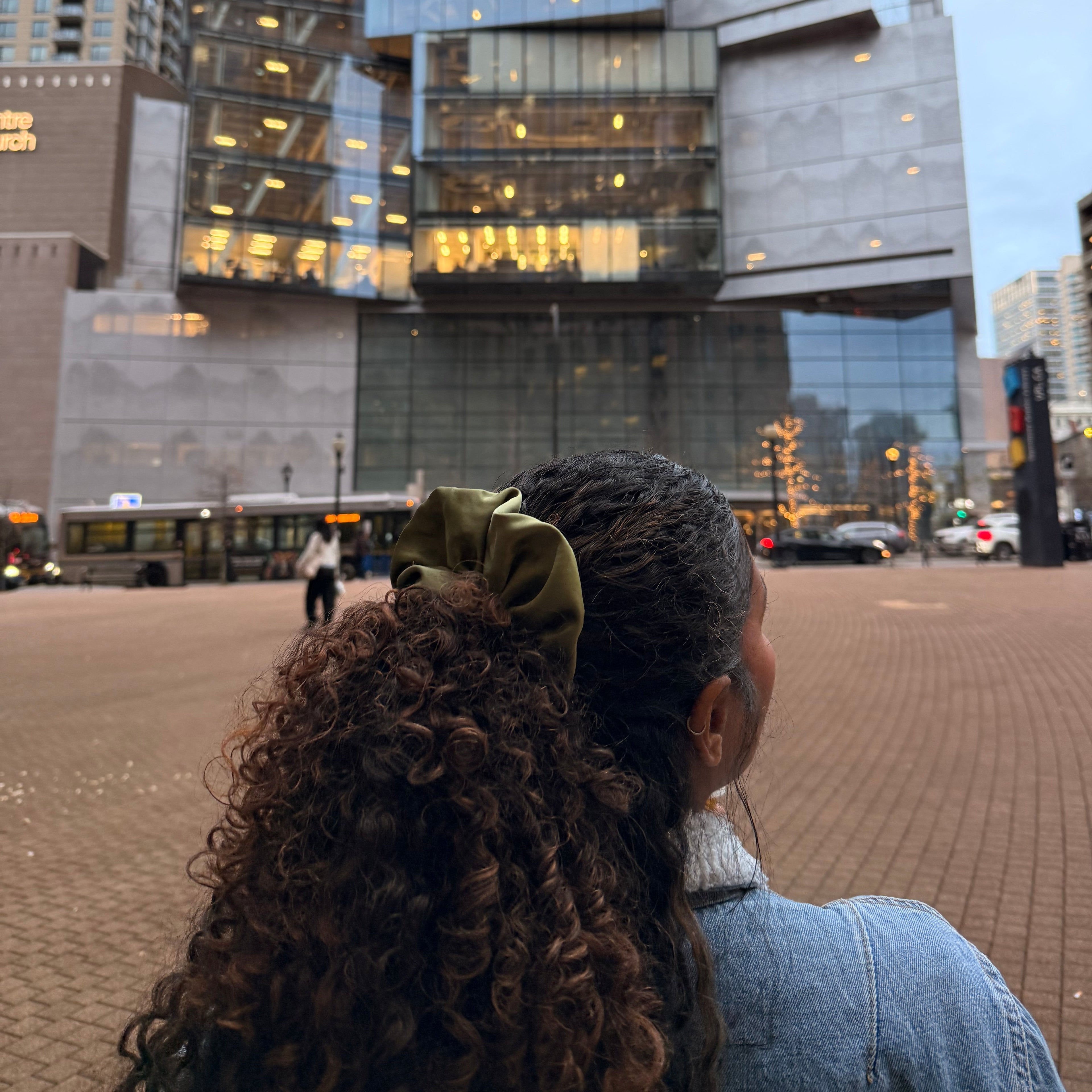 A lady with curly hair ooking at a cityscape while hearing the Xodo Soft Schrunchy in the Green shade